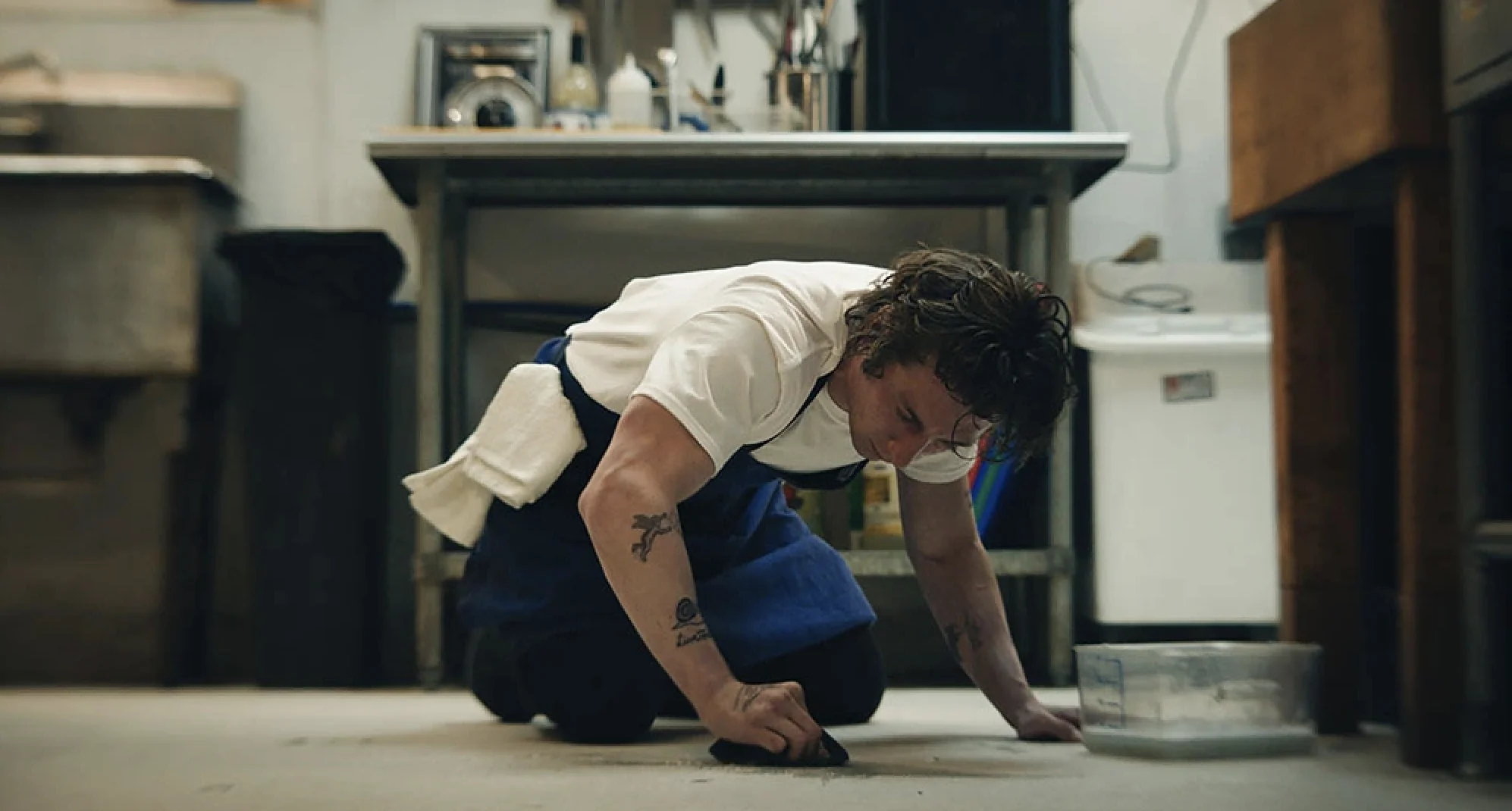 Carmy on his knees scrubbing the kitchen floor